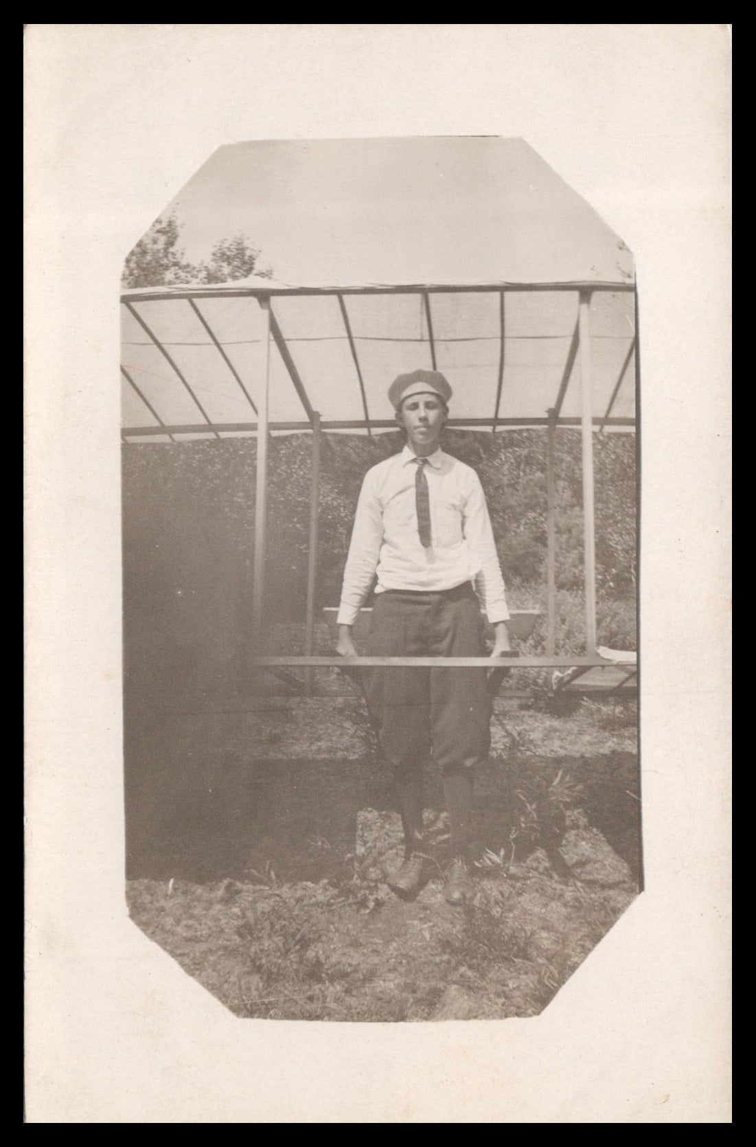 Vintage black and white photograph of a boy in front of a homemade aircraft frame. - Image: MA-PC_0025