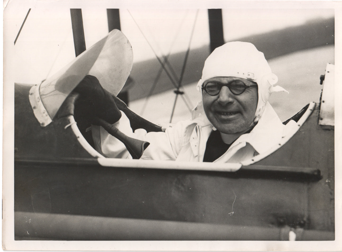 Black-and-white photo of a smiling pilot in a bi-plane cockpit - Image: Folder28-7
