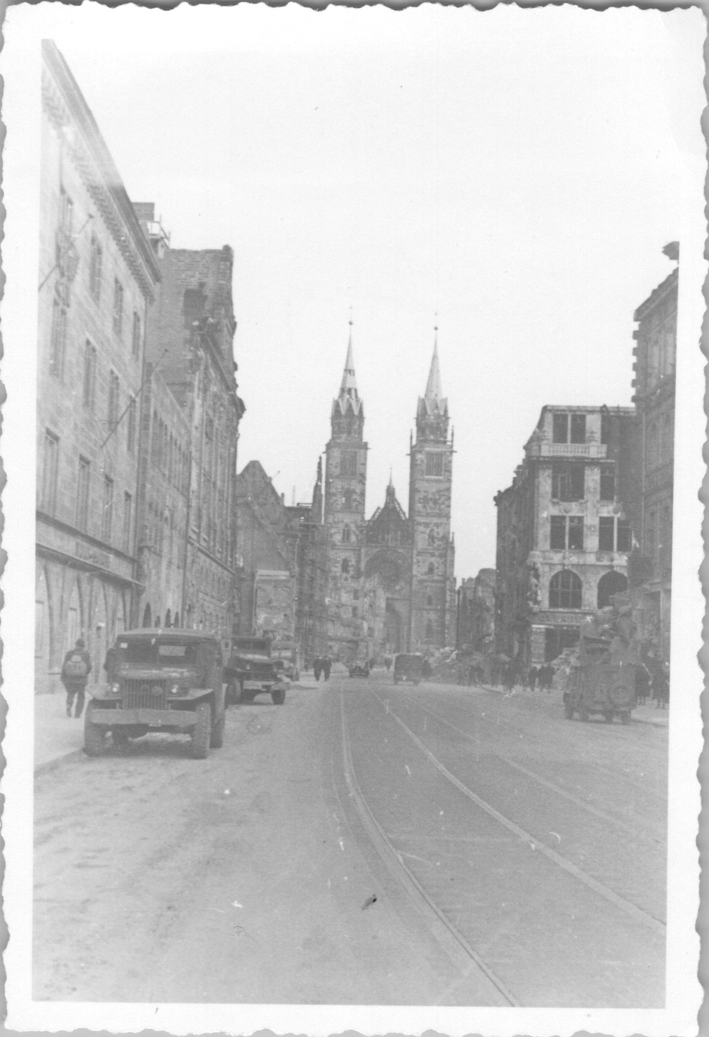 Black and white photo of a wartime street with a Gothic cathedral and vintage vehicles. - Image: 2025-08-25-0059
