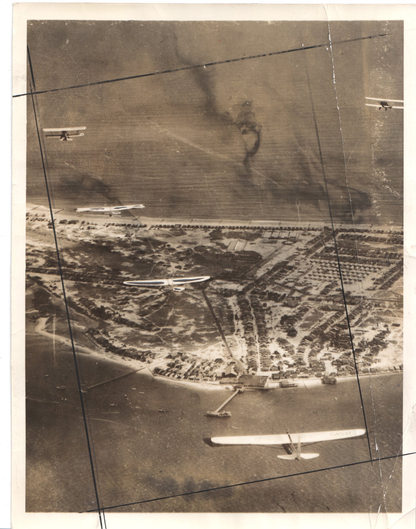 Aerial view of a coastal town with biplanes flying overhead in sepia tones. - Image: Folder27-1
