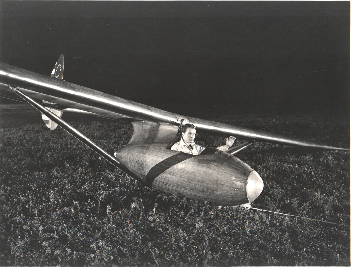 A pilot seated in a vintage wooden glider at night. - Image: Folder25-27