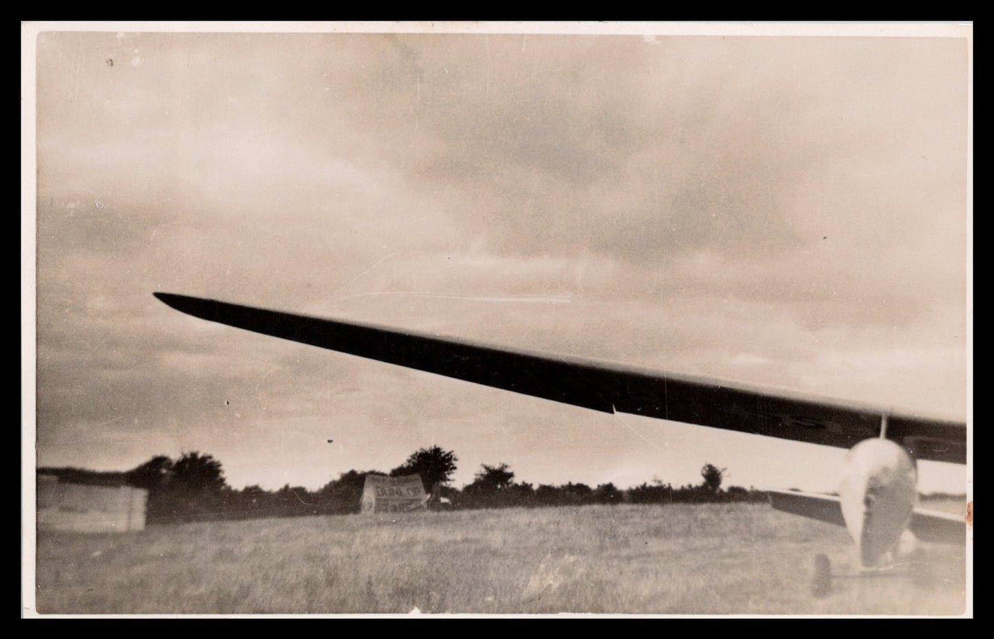 Vintage photograph of an aircraft with a wing in focus against a cloudy sky. - Image: MA-PC_0009