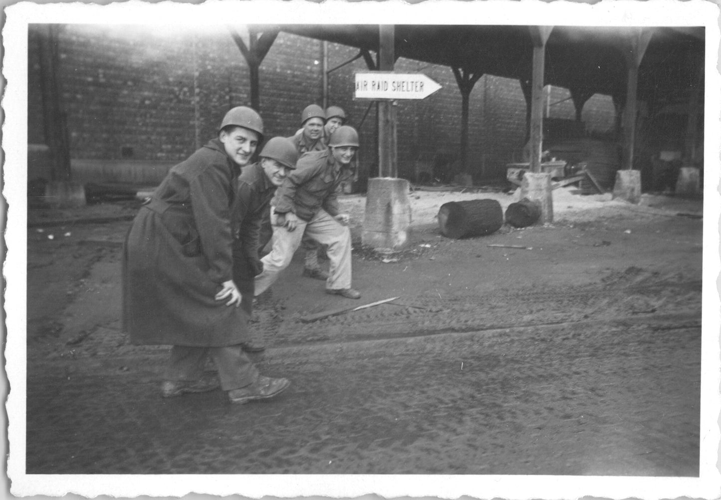 A group of five WWII soldiers posing playfully near an air raid shelter sign. - Image: 2025-08-25-0003