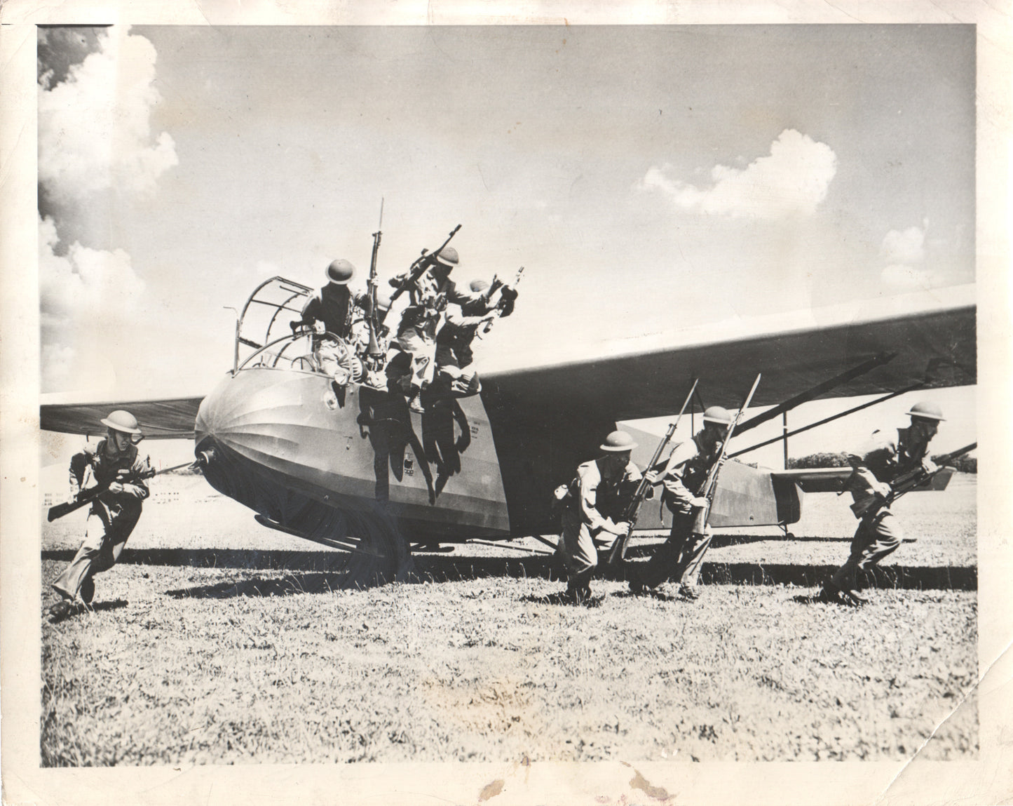 Black and white photo of WWII soldiers disembarking from a military glider. - Image: Folder16-27