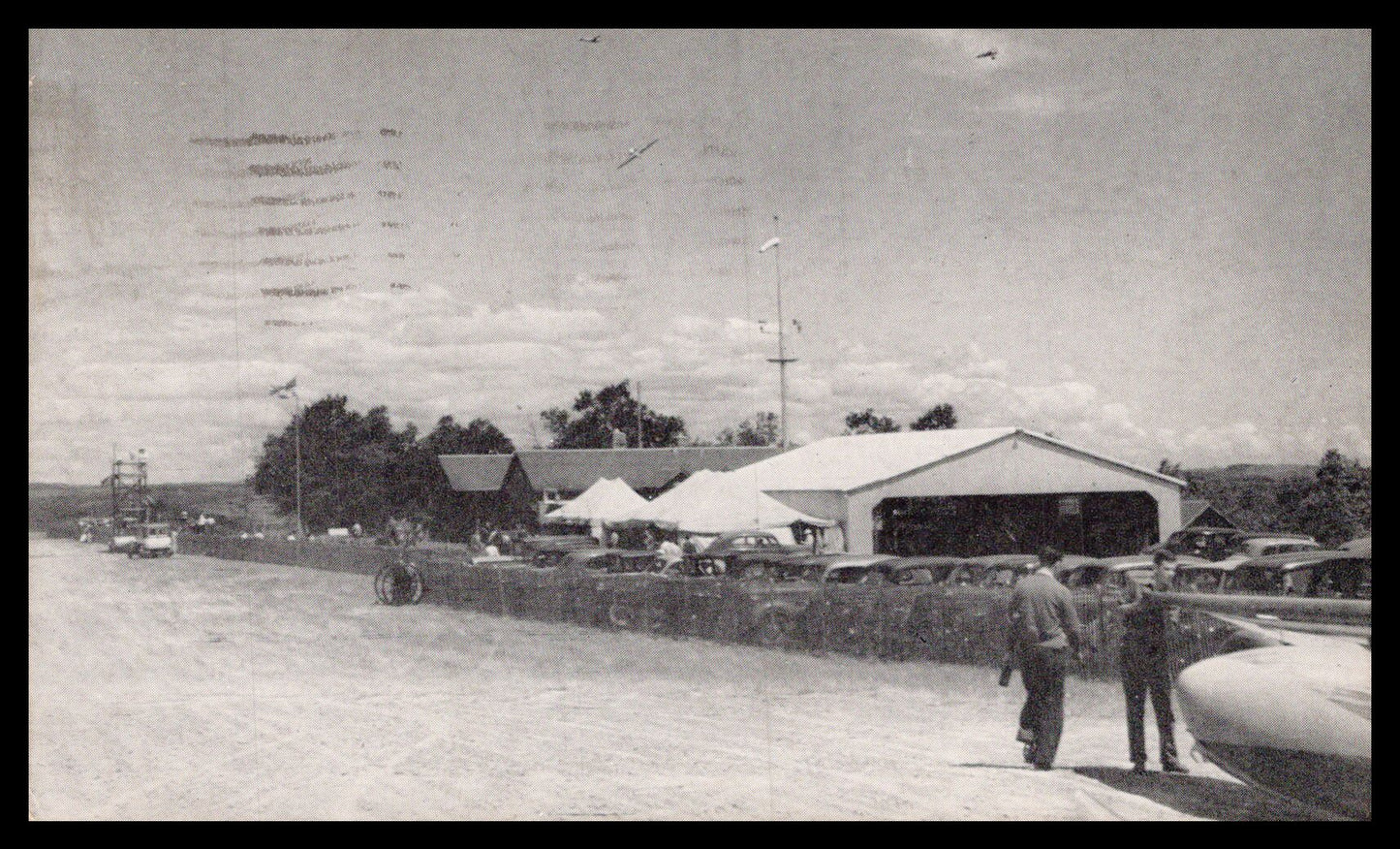 A vintage photograph of an air show featuring classic cars and people. - Image: MA-PC_0037