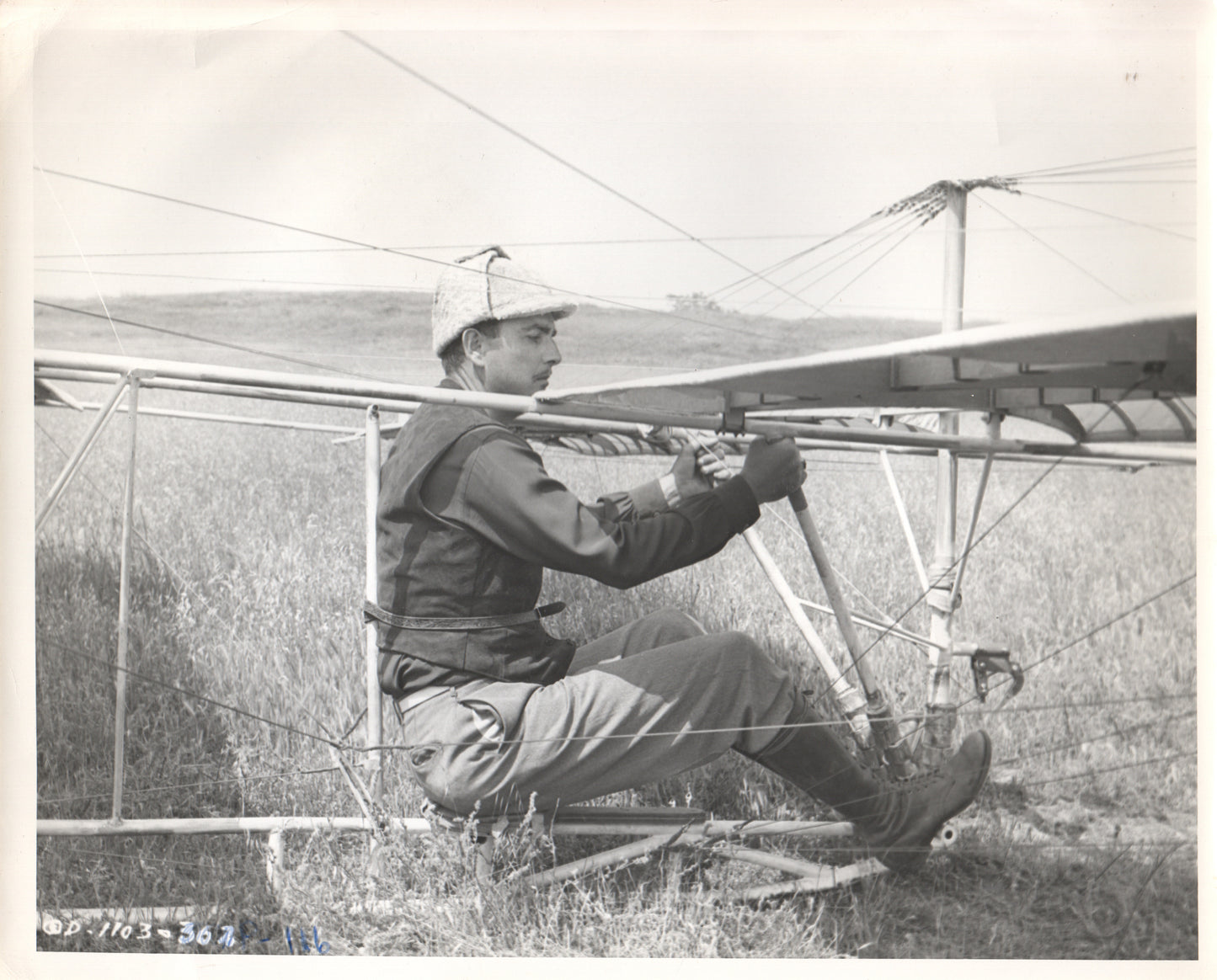 Black and white photograph of a pilot in a vintage glider preparing for flight. - Image: Folder7-7