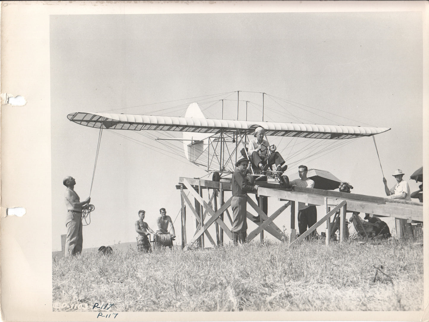 Historical photograph of early aviators preparing a biplane for flight. - Image: Folder9-13