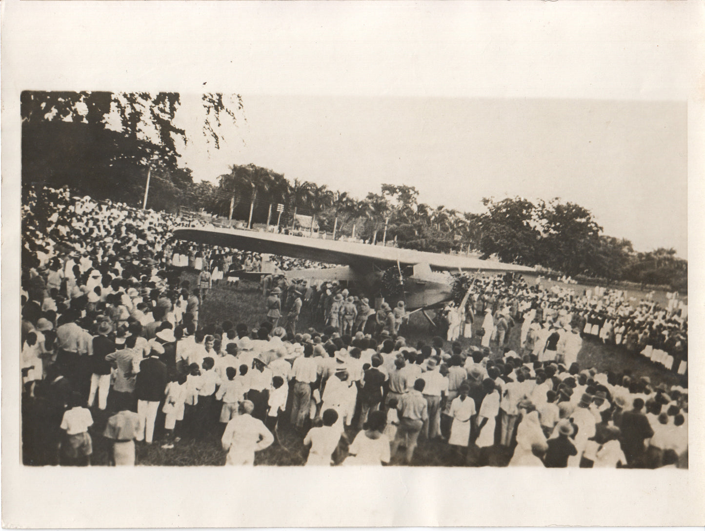 Photo of a large crowd gathered around a vintage airplane celebration. - Image: Folder19-3
