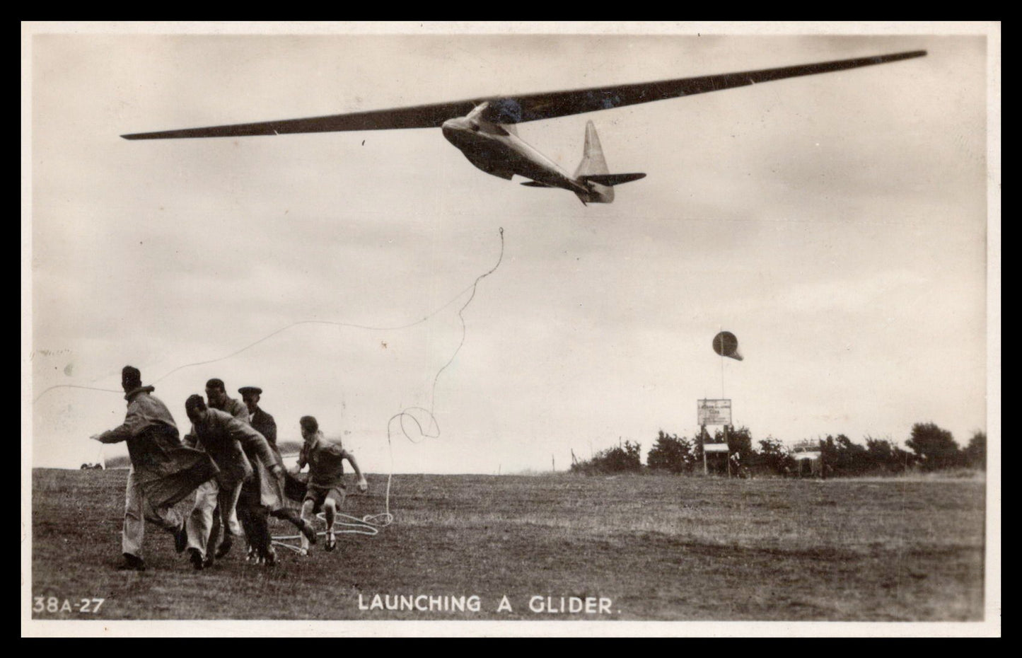 Vintage postcard depicting the launching of a glider with people running below. - Image: MA-PC_0051