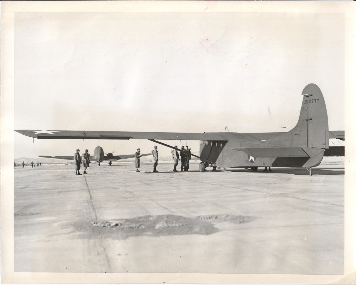 A military aircraft on an airfield with crew members nearby. - Image: Folder25-13