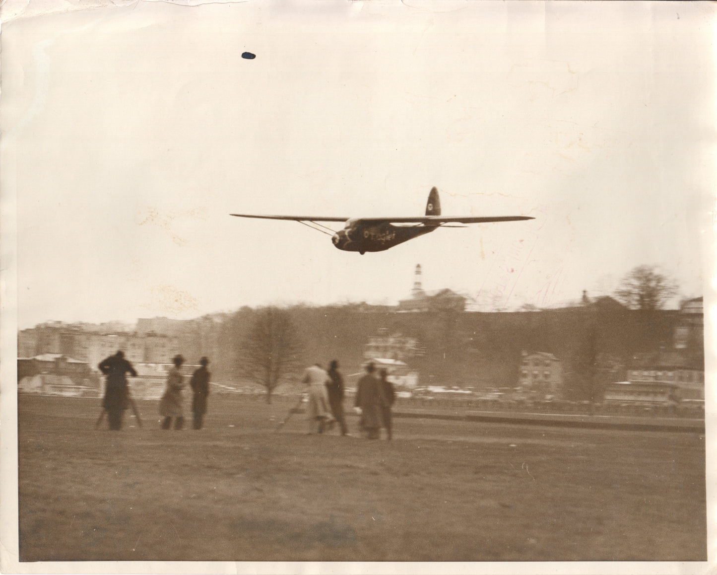 Vintage photograph of a model airplane in flight with spectators on the ground. - Image: Folder21-1