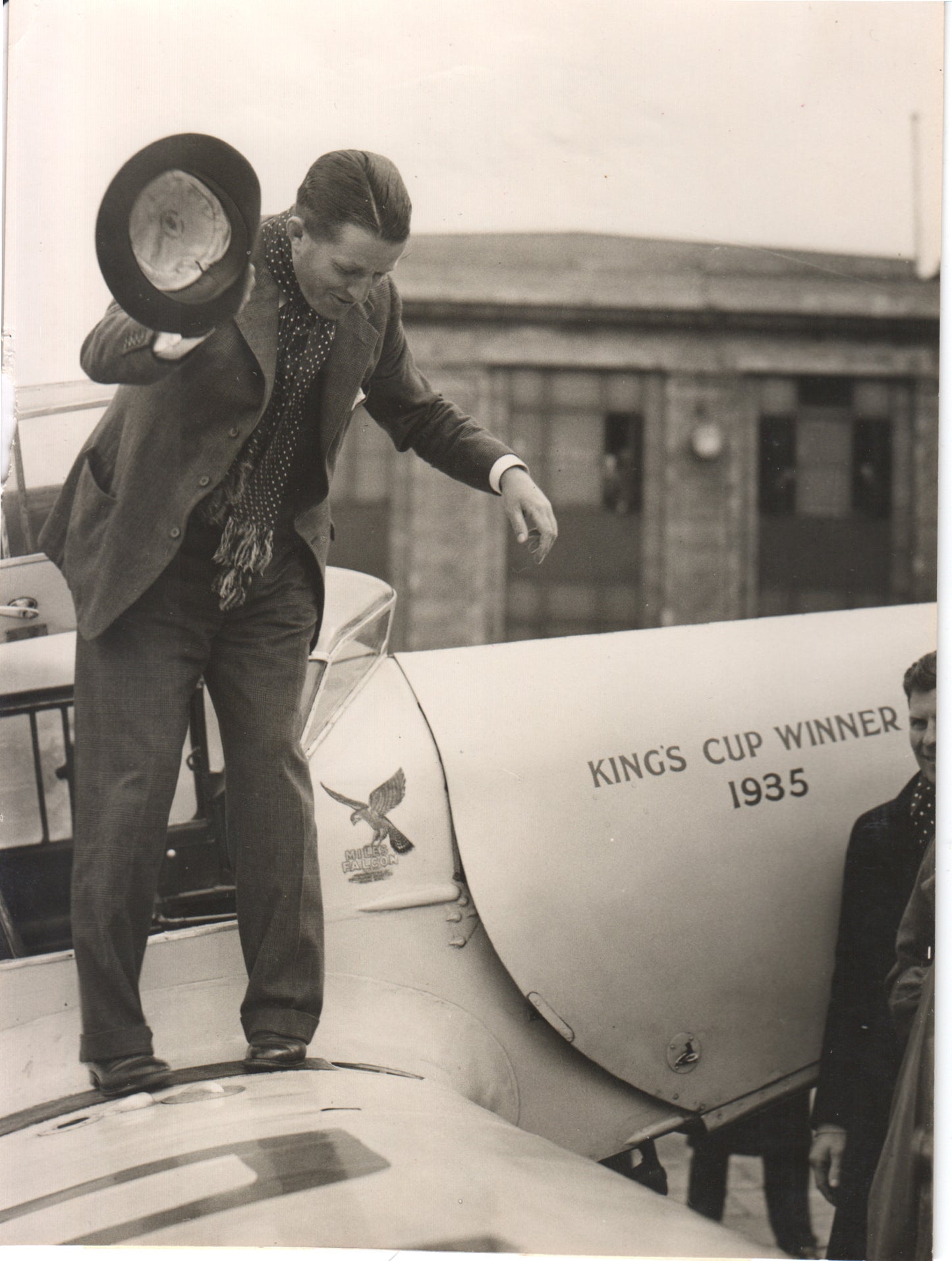 A vintage photograph of a pilot celebrating on an airplane, labeled "King's Cup Winner 1935." - Image: Folder28-11