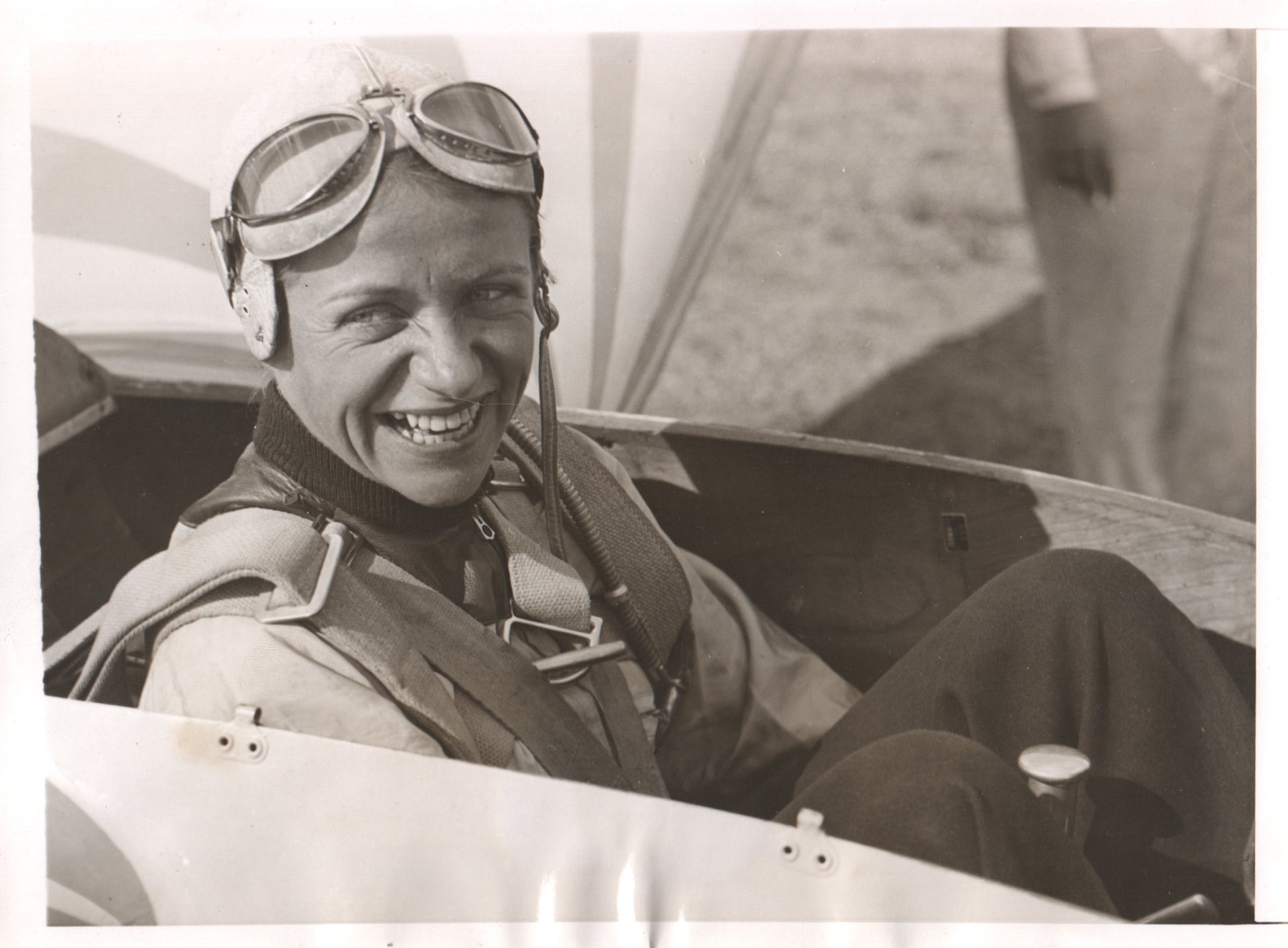 A smiling female pilot wearing flight gear in an aircraft. - Image: Folder12-7