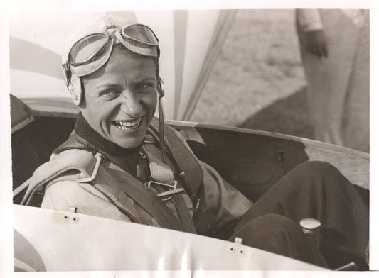 A smiling female pilot wearing flight gear in an aircraft. - Image: Folder12-7