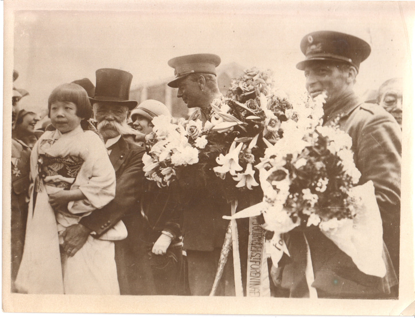 Black and white photo featuring a young girl in Japanese attire with military personnel in a celebratory scene. - Image: Folder28-15