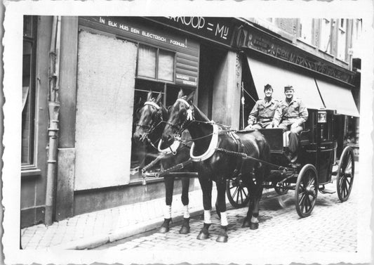 Black and white photo of a horse-drawn carriage with two soldiers on a cobblestone street. - Image: 2025-08-25-0012