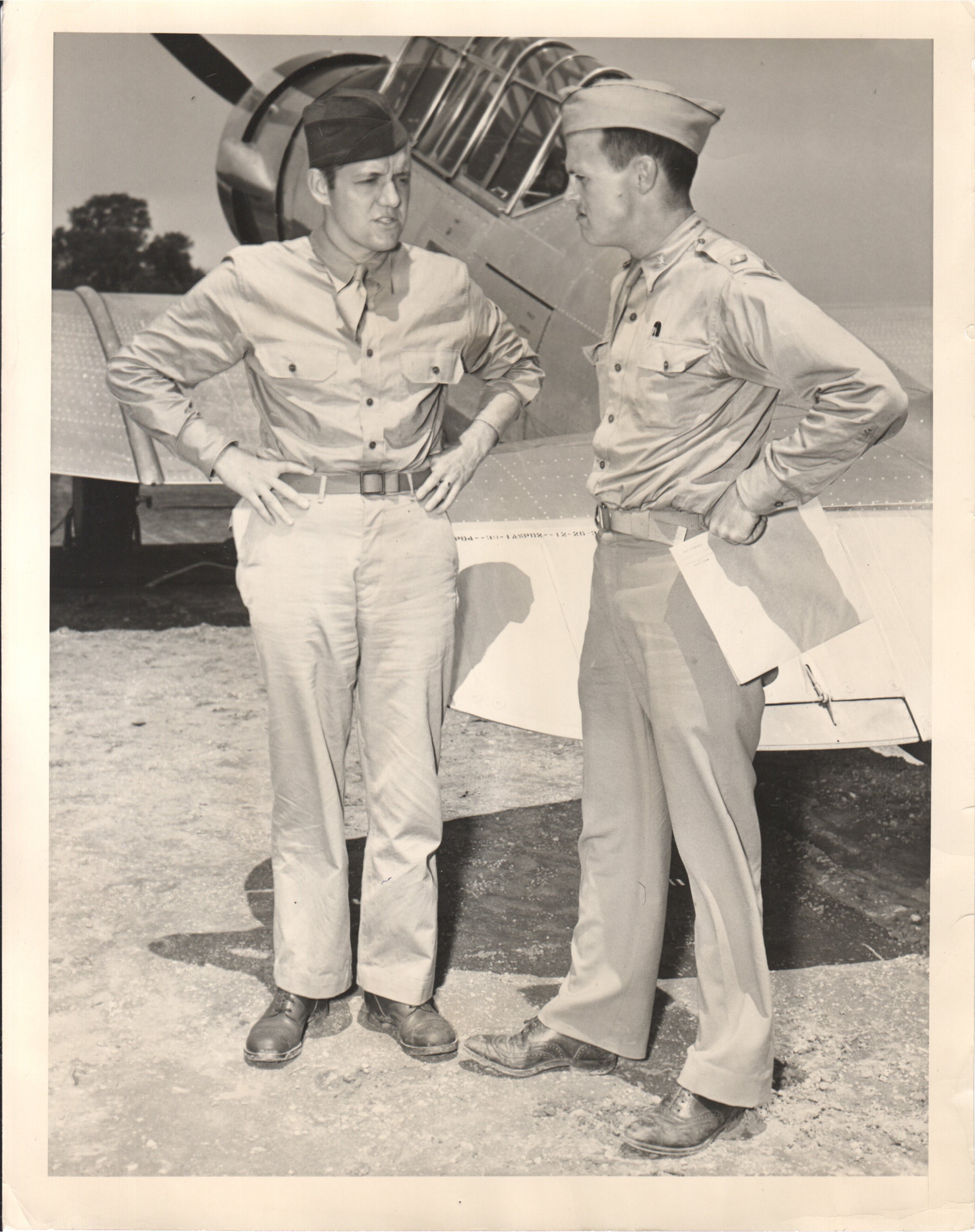 Two military personnel conversing near a WWII aircraft. - Image: Folder7-11