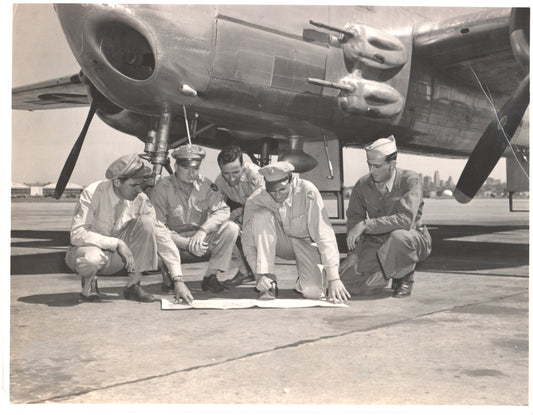 Five WWII airmen examining plans under a bomber aircraft. - Image: Folder28-25