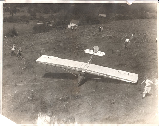 Vintage black and white photo of an early glider on a hillside with people preparing for flight. - Image: Folder20-9