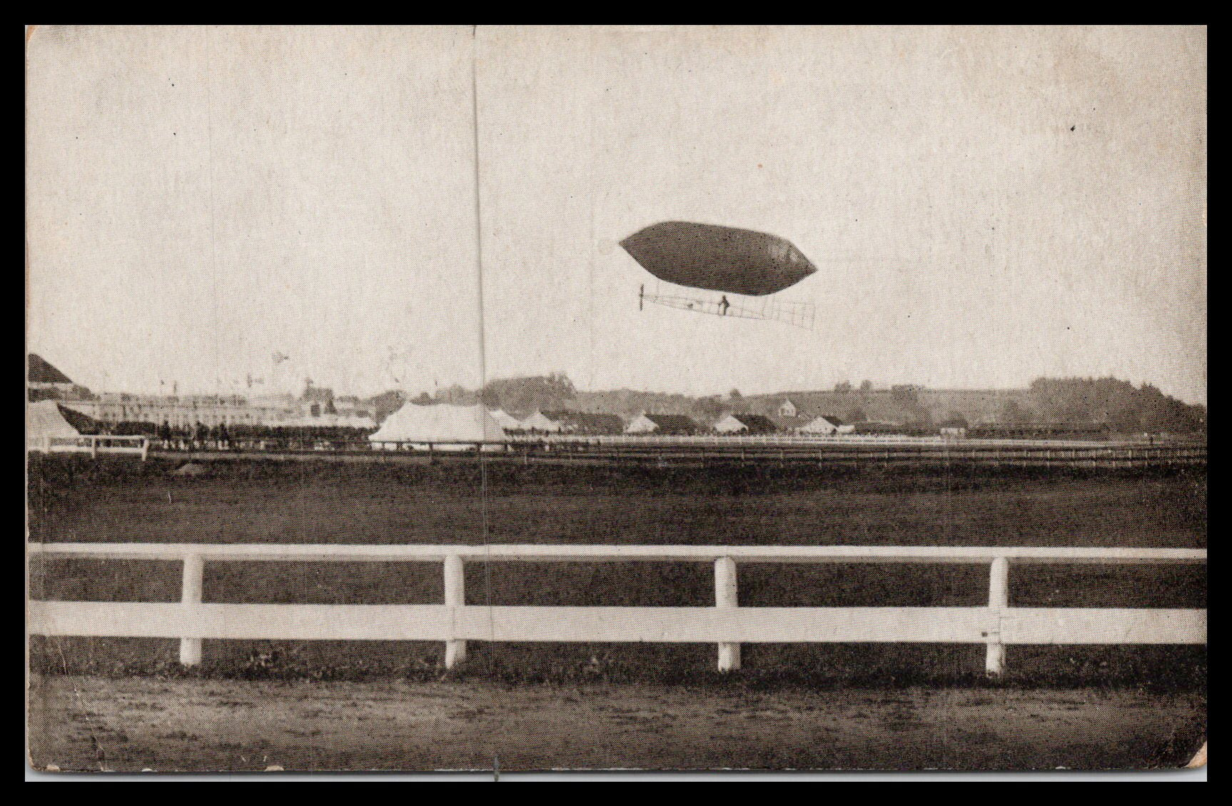 Vintage postcard depicting an airship flying over a field. - Image: MA-PC_0041