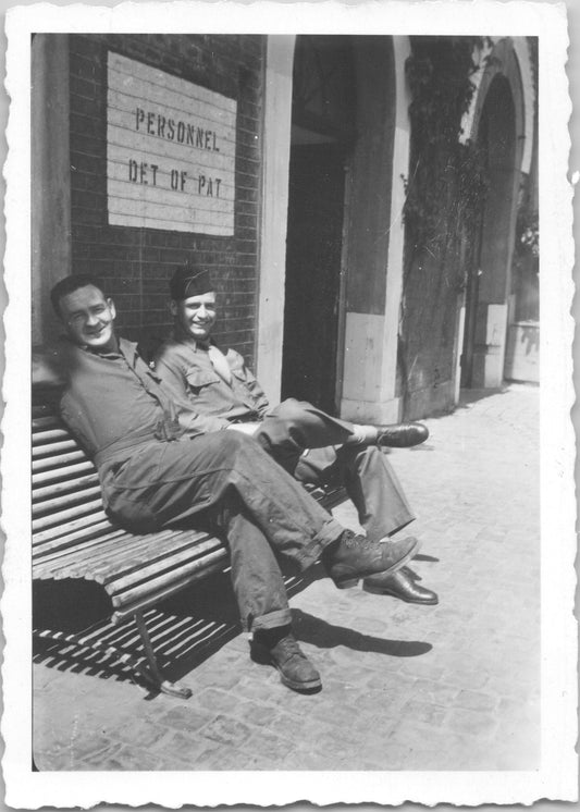 Vintage black-and-white photo of two soldiers seated on a bench at a personnel detachment. - Image: 2025-08-25-0011