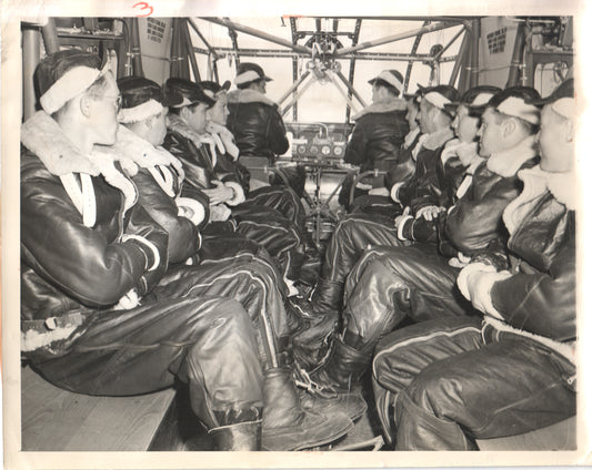 Historic black and white photograph of WWII aviators in flight suits seated inside an aircraft. - Image: Folder17-1