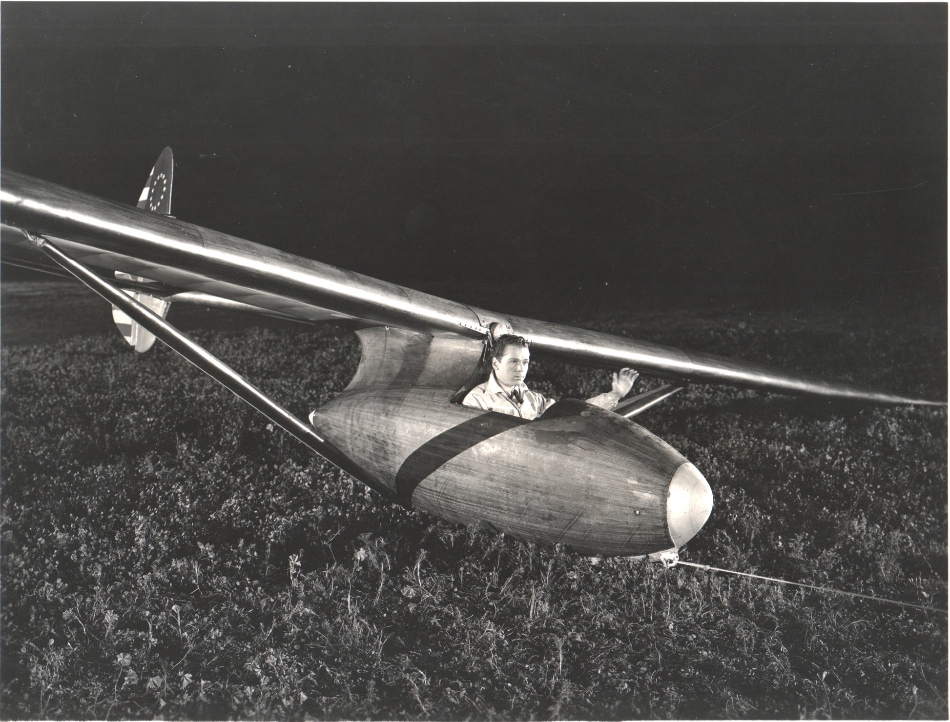 A pilot seated in a vintage wooden glider at night. - Image: Folder25-27
