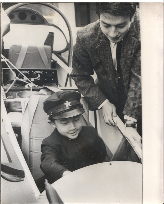 A smiling child in a pilot's seat, guided by an adult in a vintage airplane. - Image: Folder22-6
