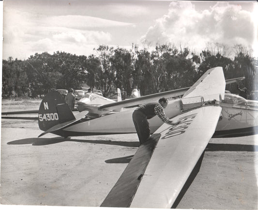 A pilot tuning a glider with tail number N54300 in a vintage photograph.