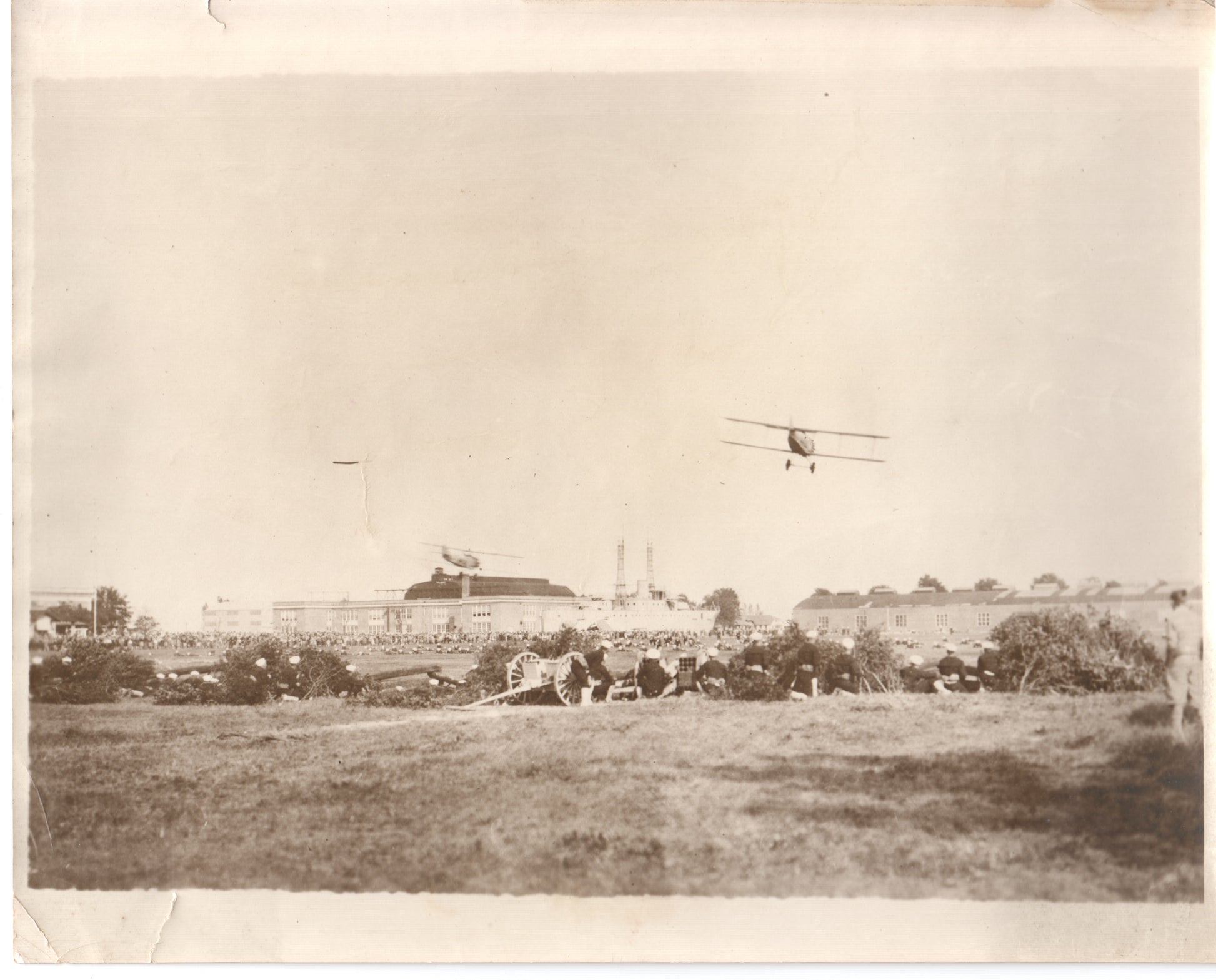 Vintage photograph of a biplane flying over a crowd gathered in a field. - Image: Folder16-15