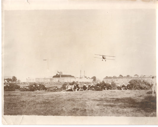 Vintage photograph of a biplane flying over a crowd gathered in a field. - Image: Folder16-15