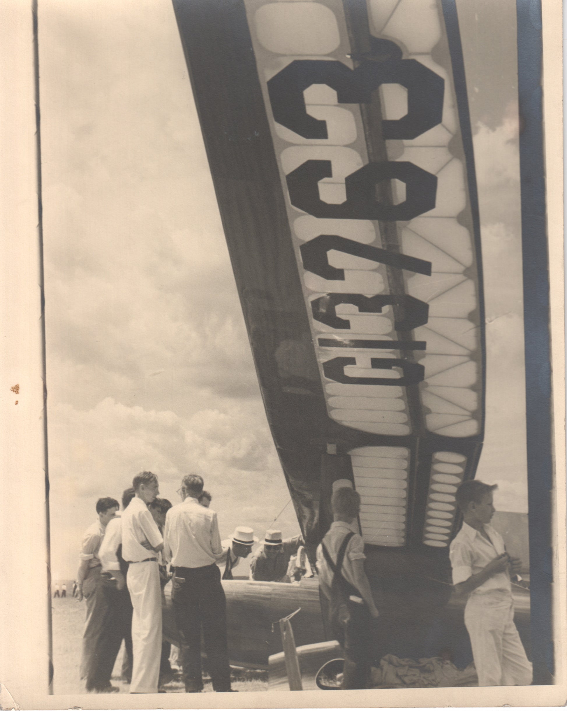 Black-and-white photograph of people gathered around a vintage aircraft. - Image: Folder18-10