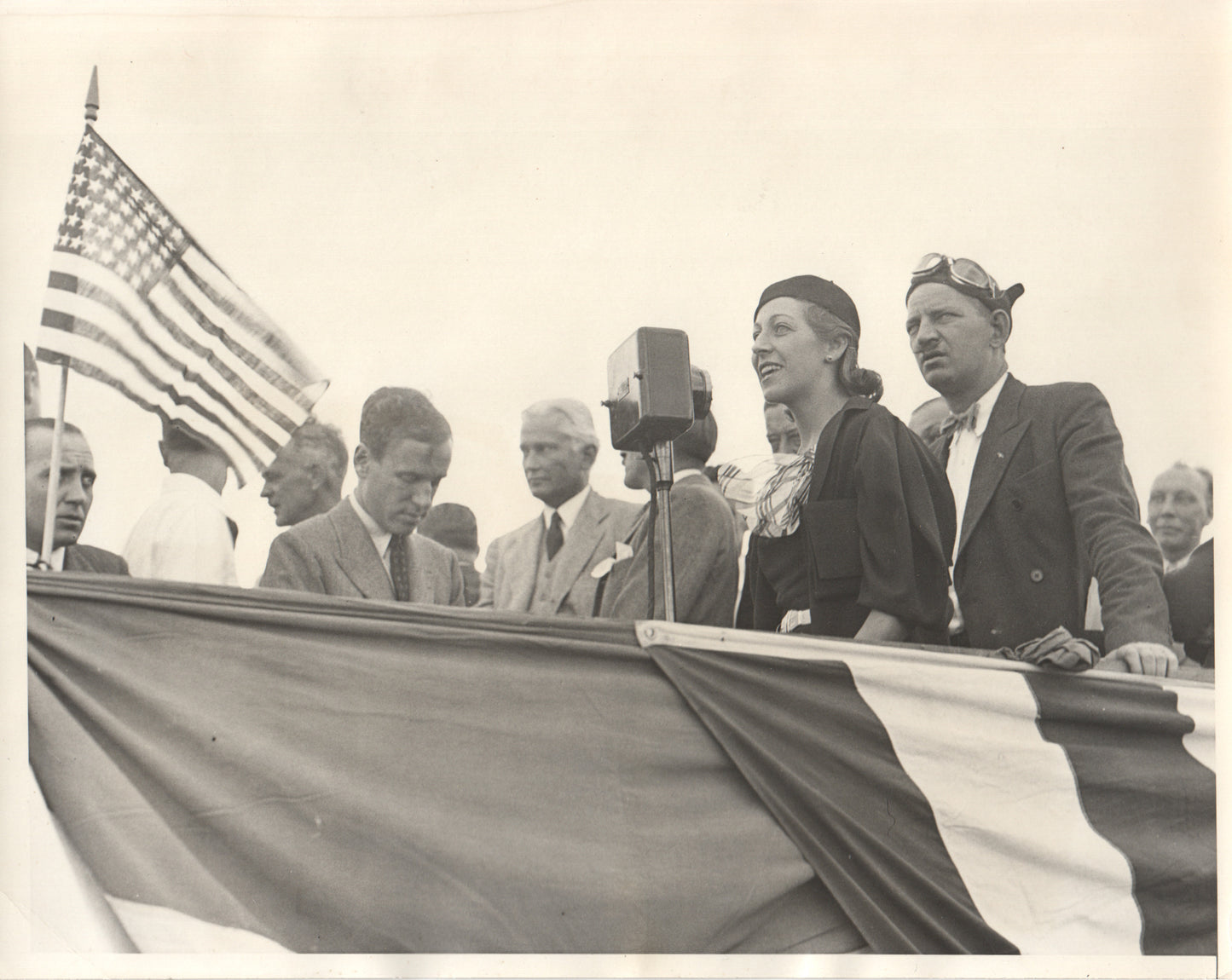 Vintage black and white photograph of a historical speech event with an American flag. - Image: Folder18-1