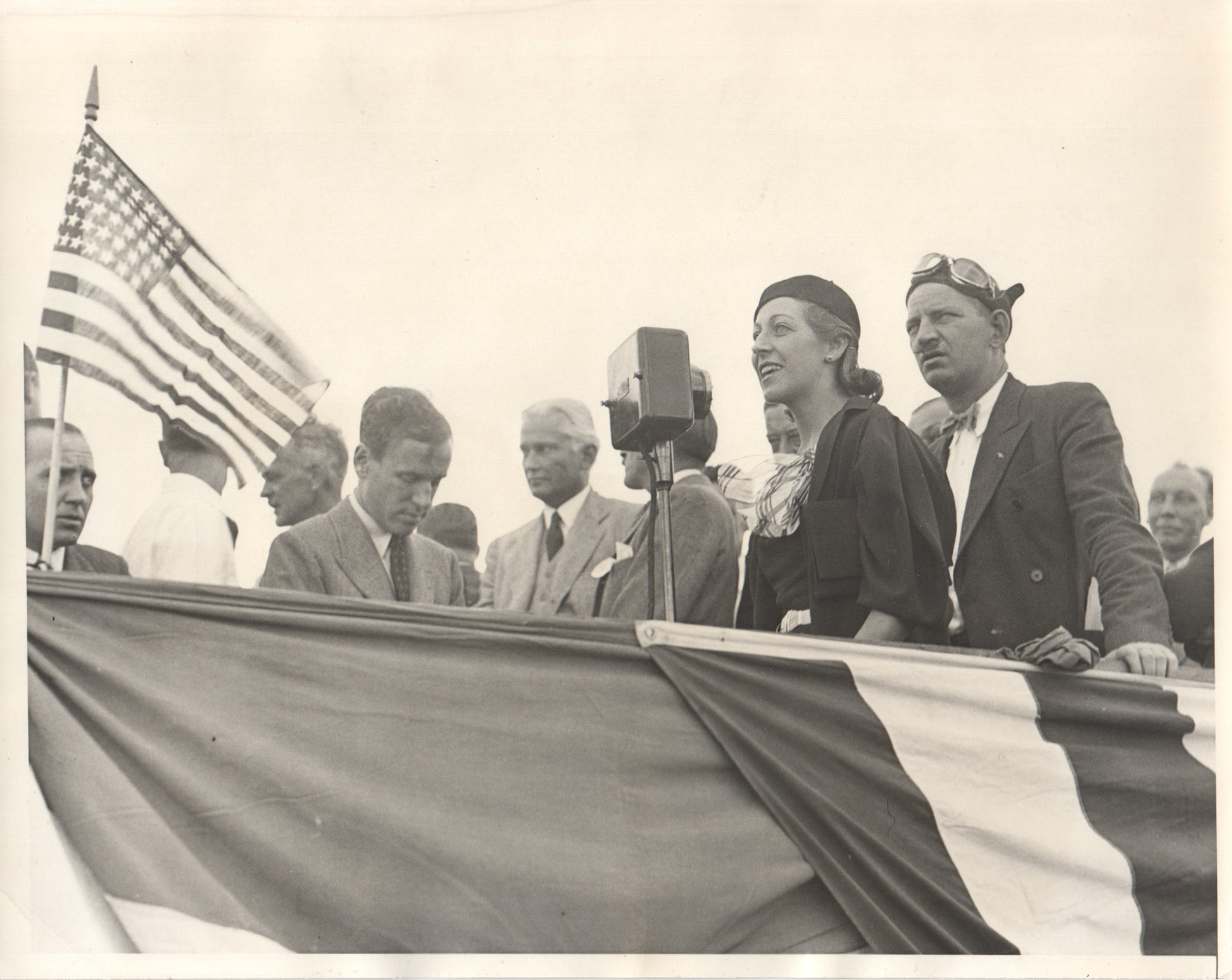 Vintage black and white photograph of a historical speech event with an American flag. - Image: Folder18-1