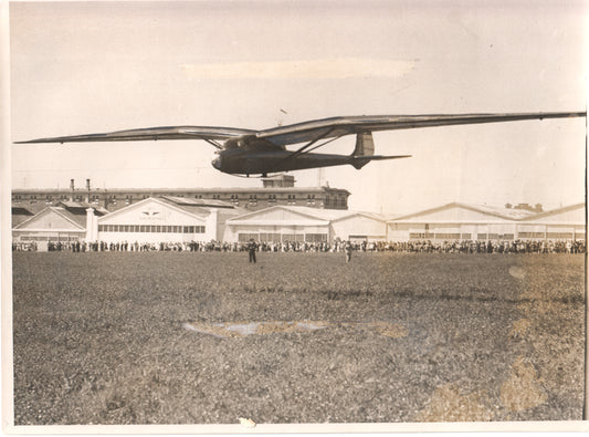 Vintage photograph of a glider in flight over a crowd at an airfield. - Image: Folder15-9
