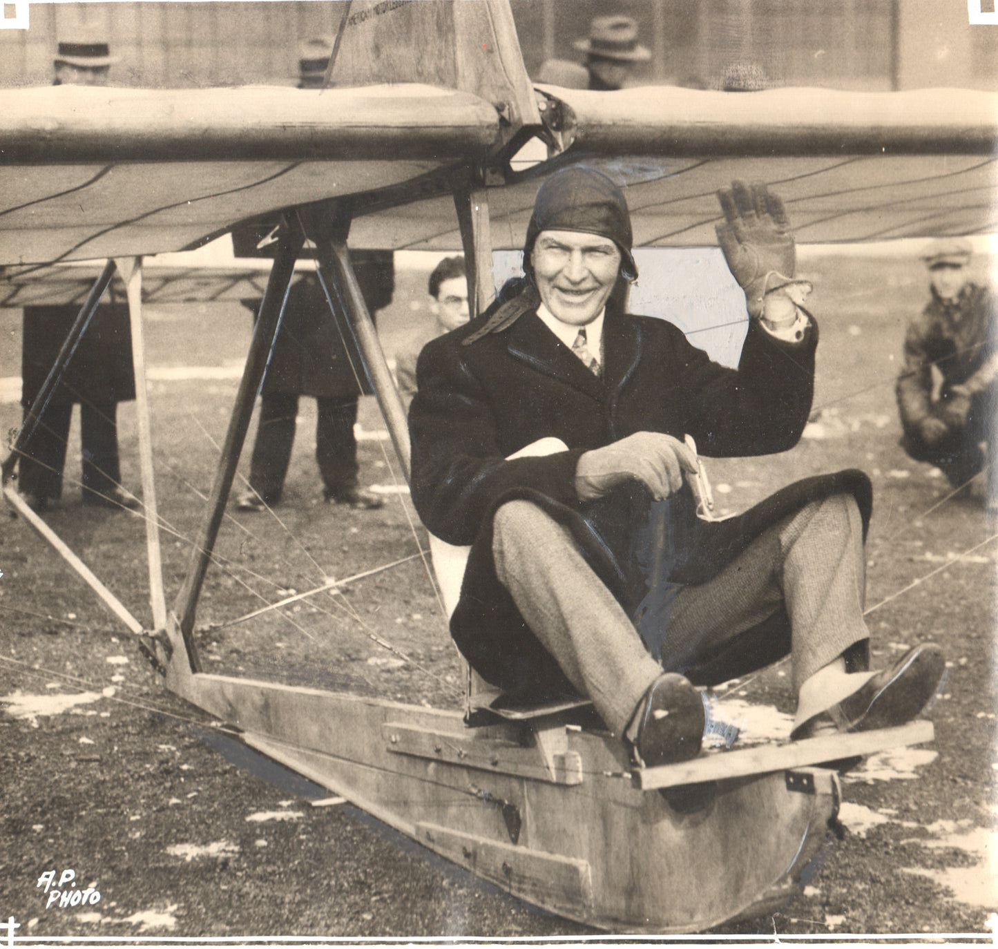 Vintage photograph of a pilot waving while seated in an early aircraft. - Image: Folder17-17