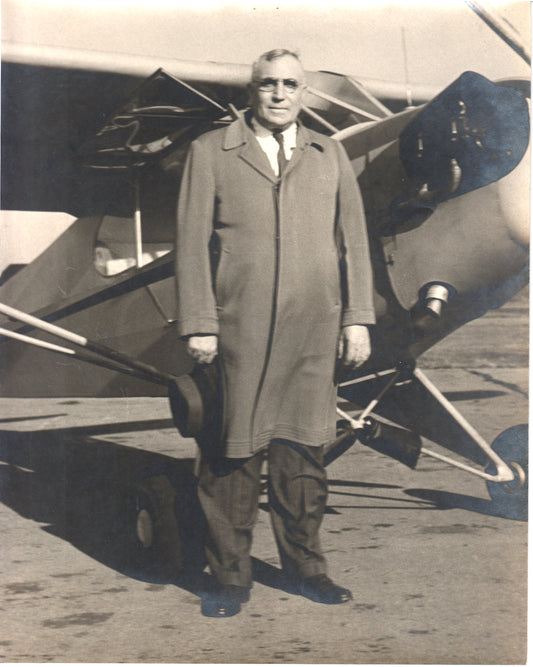 A gentleman in an overcoat standing next to a vintage airplane. - Image: Folder28-21