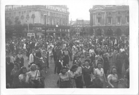 Black and white photograph of a large crowd in a public square with a grand hotel in the background. - Image: 2025-08-25-0078