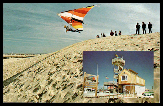 Vintage postcard featuring a hang glider over sand dunes and a beach view. - Image: MA-PC_0001