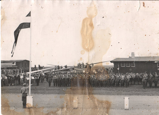 Vintage black and white photograph of a military parade with soldiers and a flag raising ceremony. - Image: Folder3-7