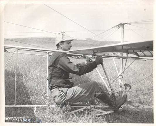Black and white photograph of a pilot in a vintage glider preparing for flight. - Image: Folder7-7