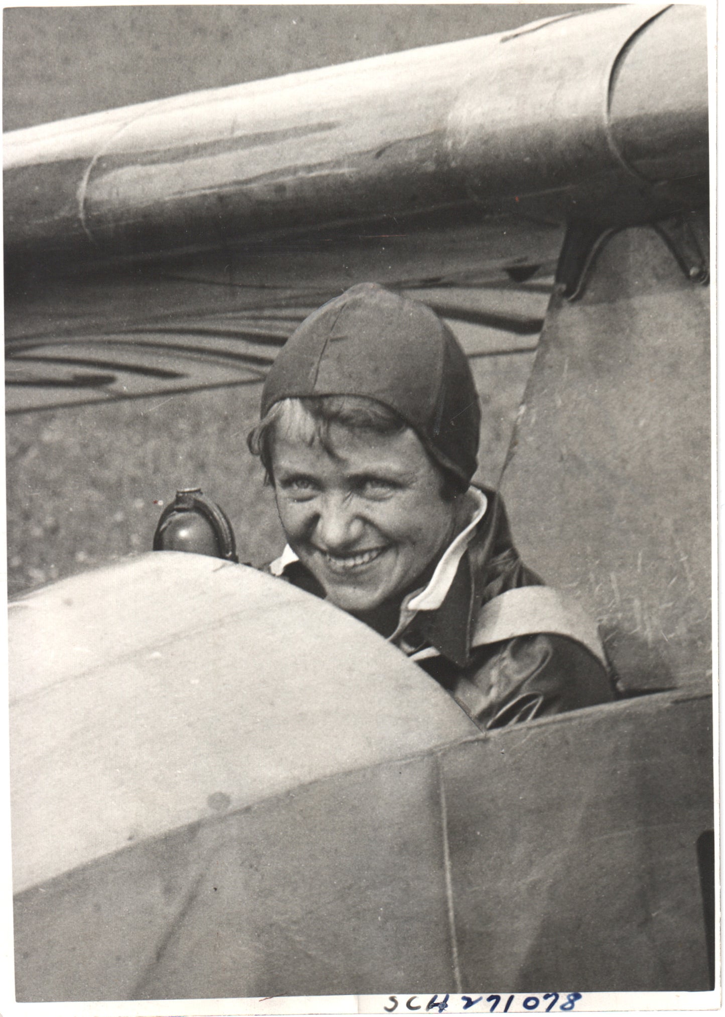 Vintage photograph of a smiling female pilot in a biplane cockpit. - Image: Folder12-9