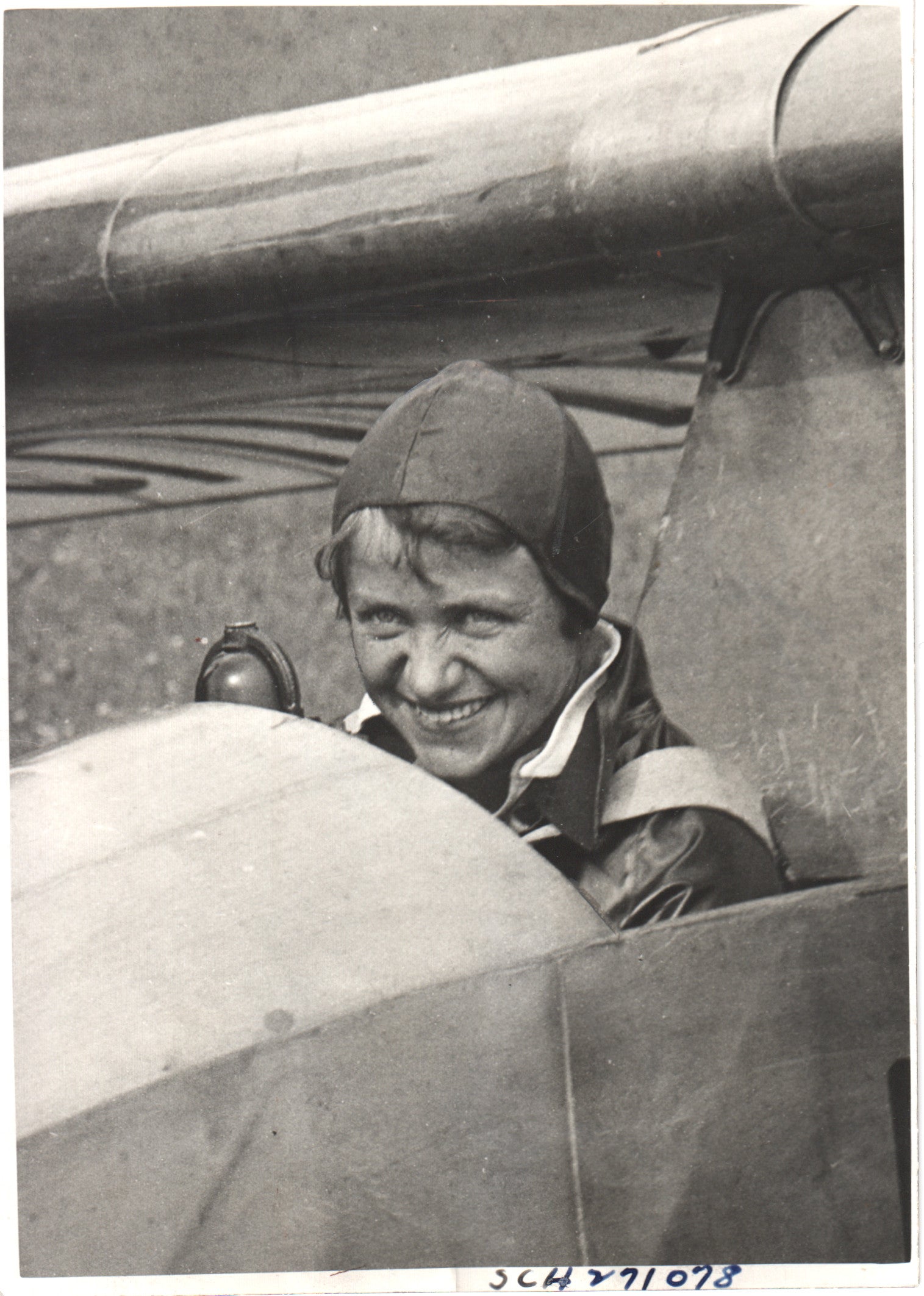 Vintage photograph of a smiling female pilot in a biplane cockpit. - Image: Folder12-9
