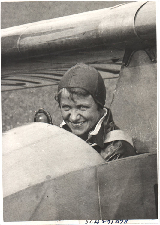 Vintage photograph of a smiling female pilot in a biplane cockpit. - Image: Folder12-9