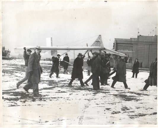Early aviators carrying a glider in a snowy setting. - Image: Folder17-15