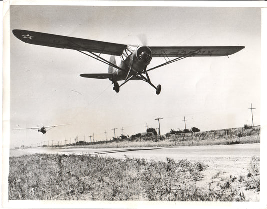 Black-and-white photo of a U.S. Army bi-plane in flight over a rural landscape. - Image: Folder25-25