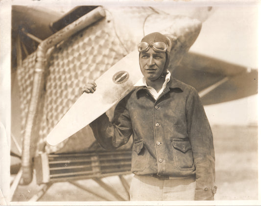 Vintage photograph of an aviator in leather jacket with goggles standing by an airplane. - Image: Folder19-10