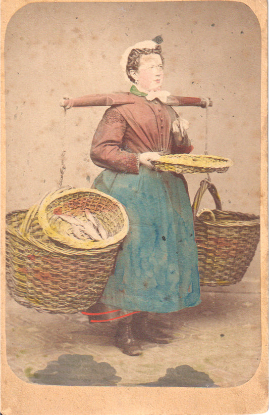 Hand-colored vintage photograph of a woman dressed as a fish vendor with baskets. - Image: 2025-04-18-0067