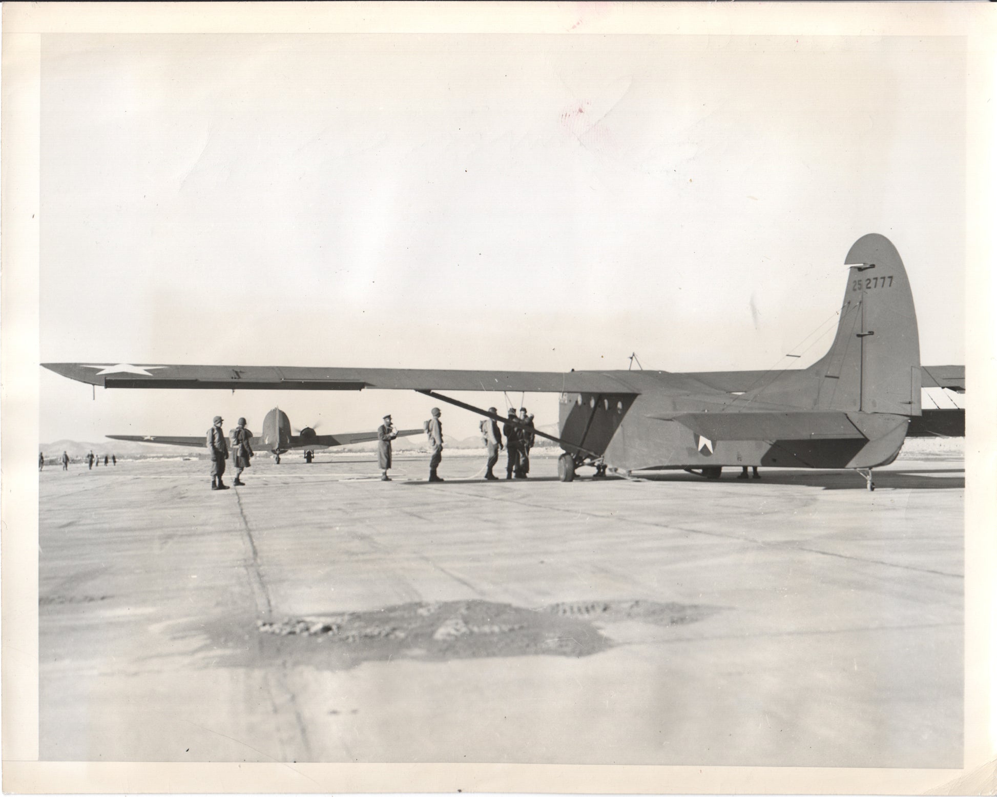 A military aircraft on an airfield with crew members nearby. - Image: Folder25-13