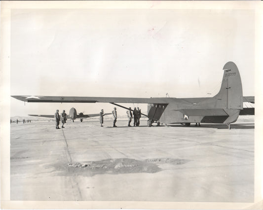 A military aircraft on an airfield with crew members nearby. - Image: Folder25-13